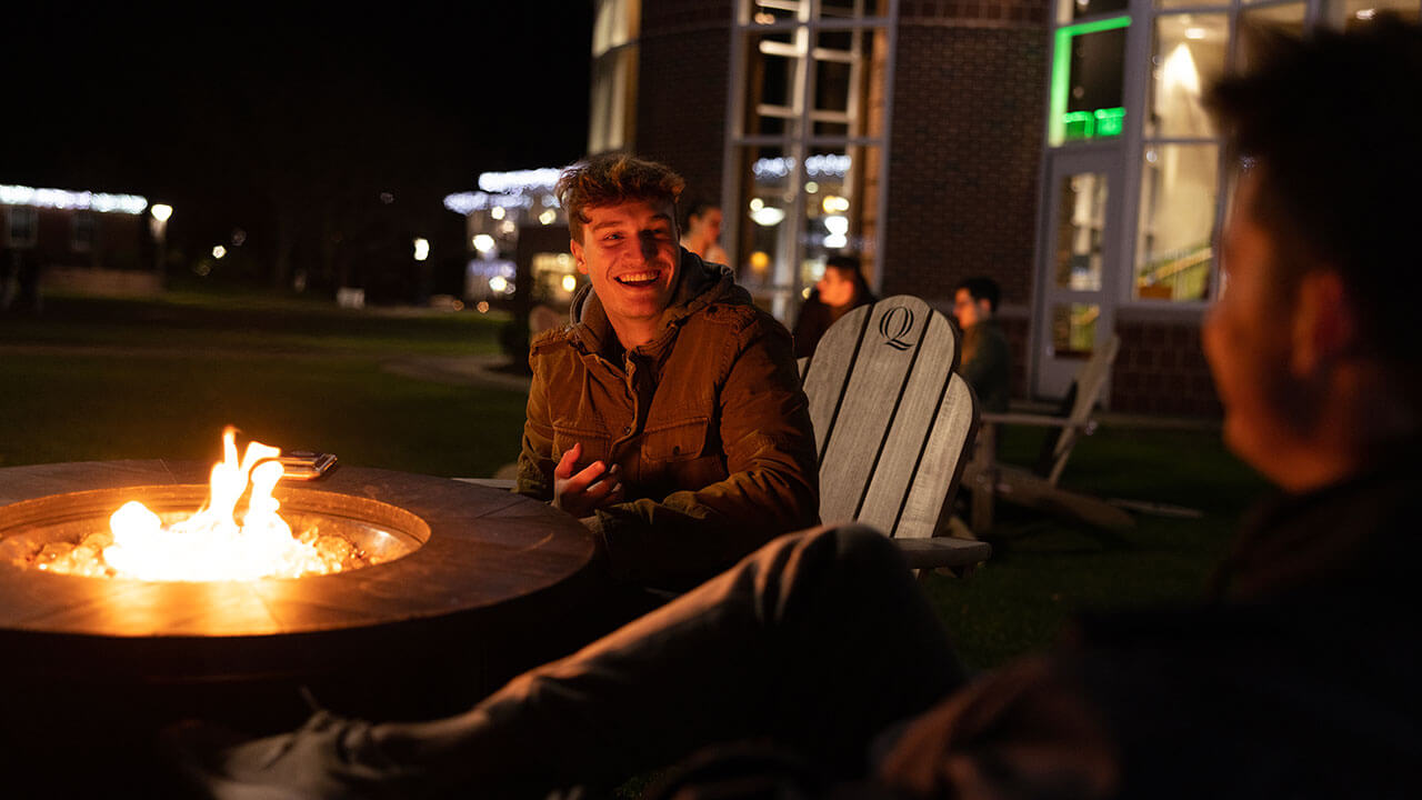 Two students laugh while warming up on the Quad