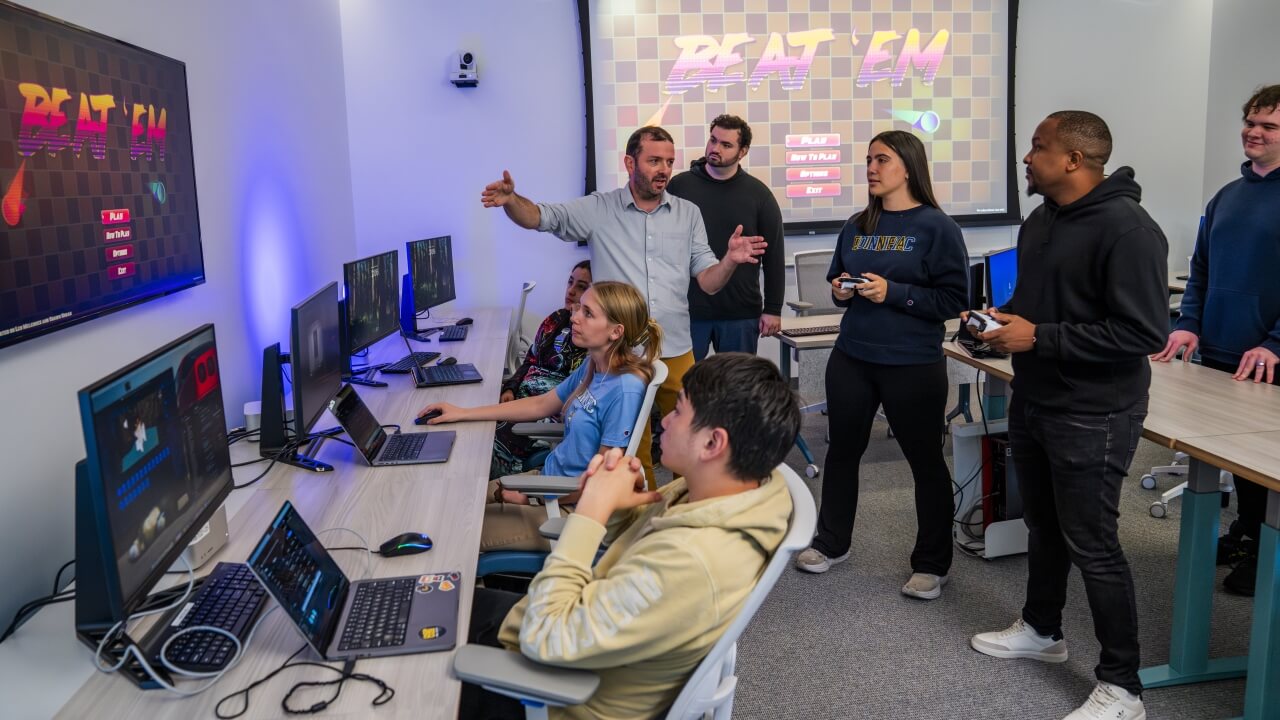 Professor speaking to a group of students in a computer lab