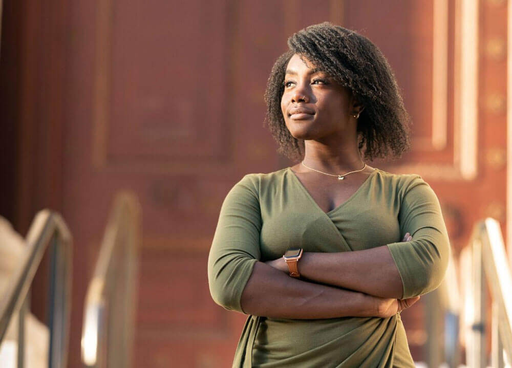 Quaye standing outside with her arms crossed looking to the left