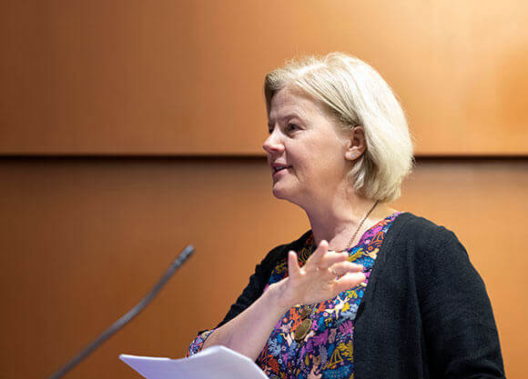 Beth Macy stands at a podium with a microphone speaking