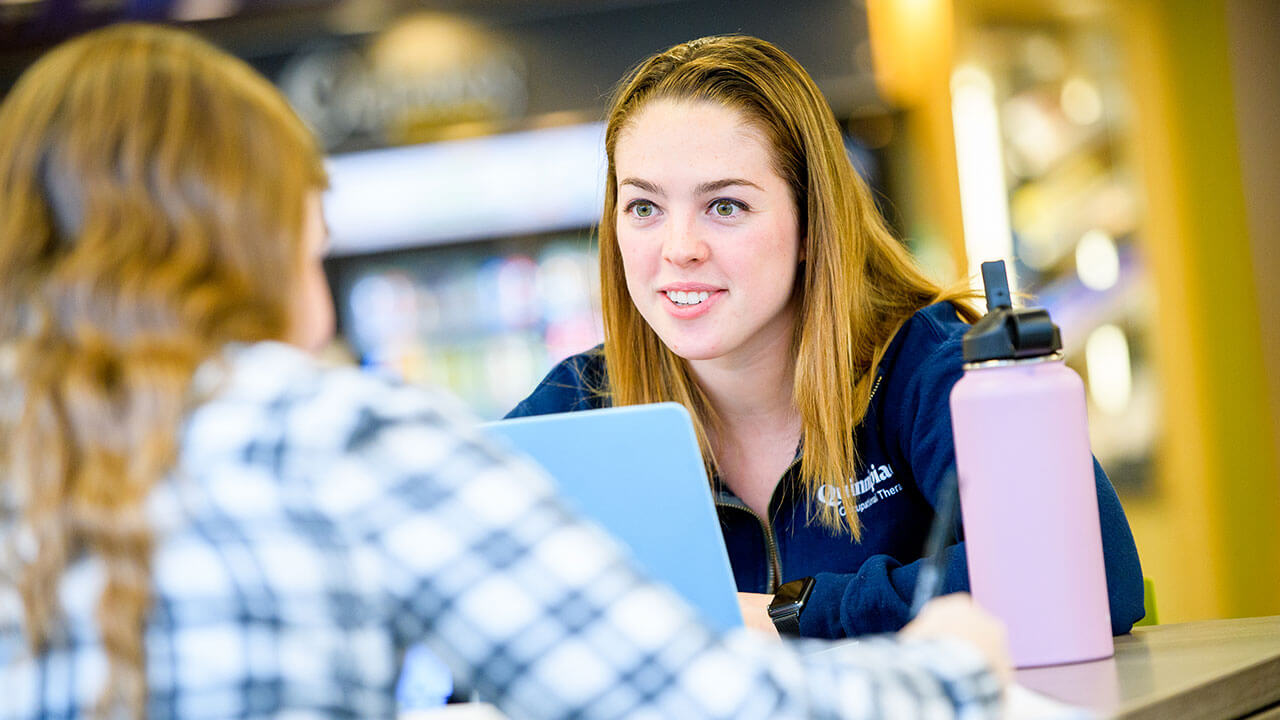 woman talking in library to another woman