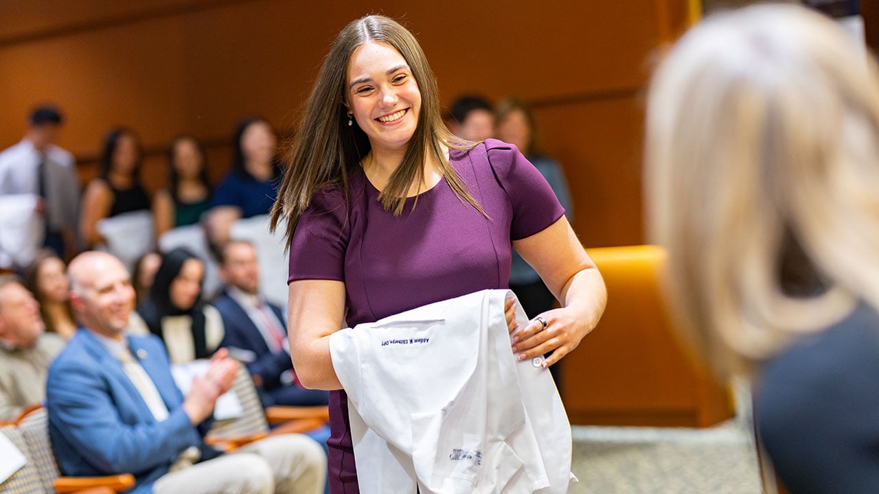 Student smiles with their white coat
