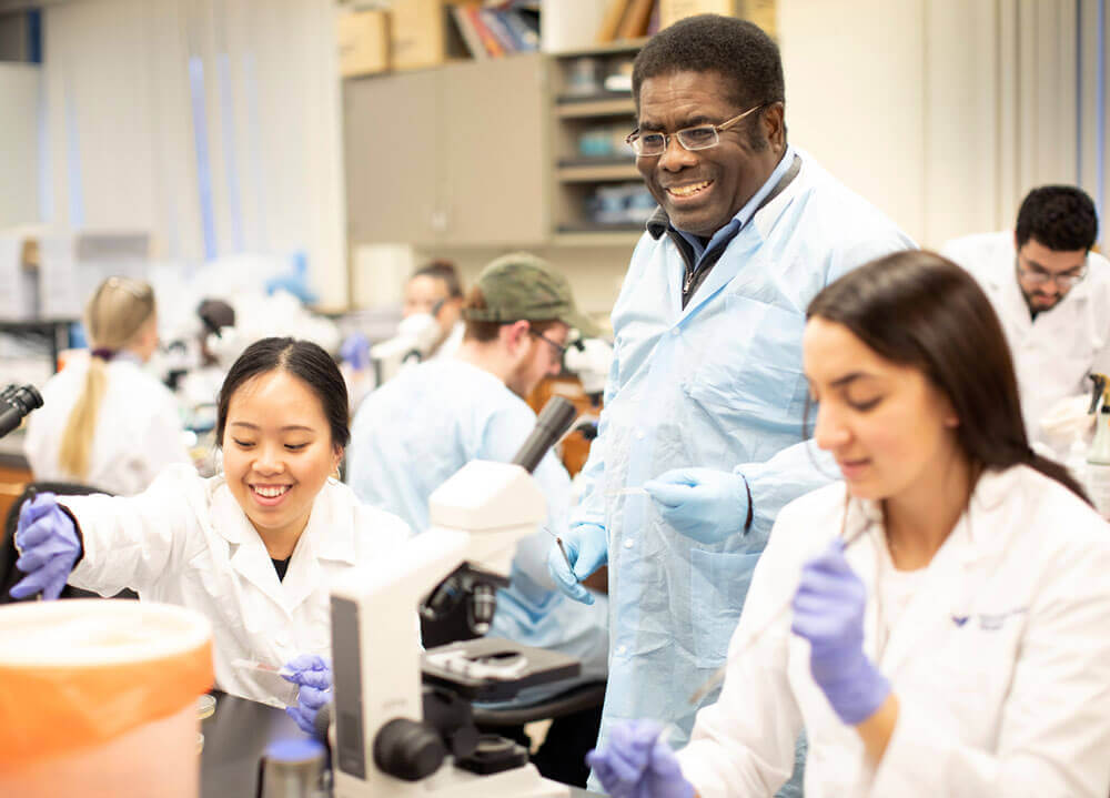 Professor Harewood works in a lab with students.