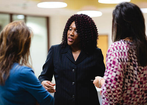 Fay Brown, PhD, stands talking to two other women.
