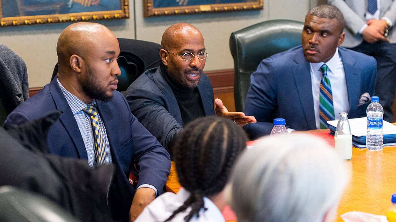 Don Sawyer and Van Jones sit with a group of people having a conversation at a table.