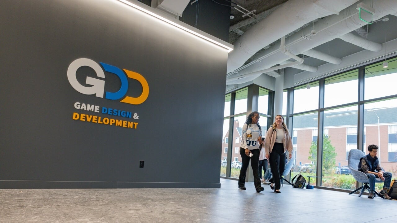 Students walking in front of the Game Design and Development sign in the SITE