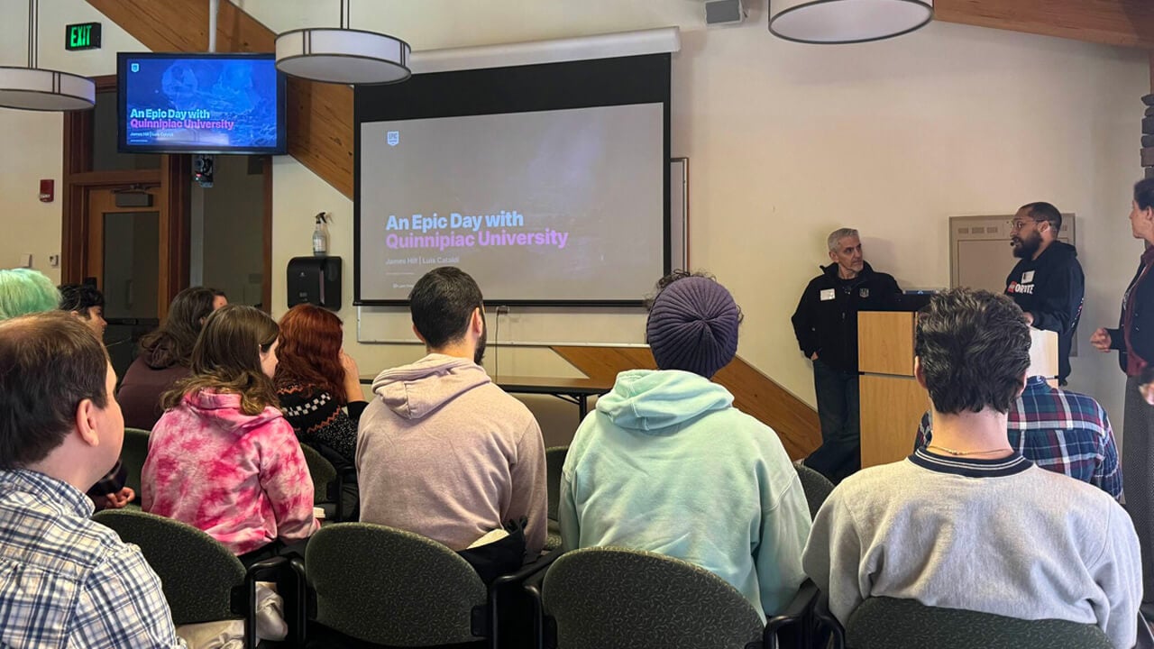 Student sitting in rows watching 3 people present