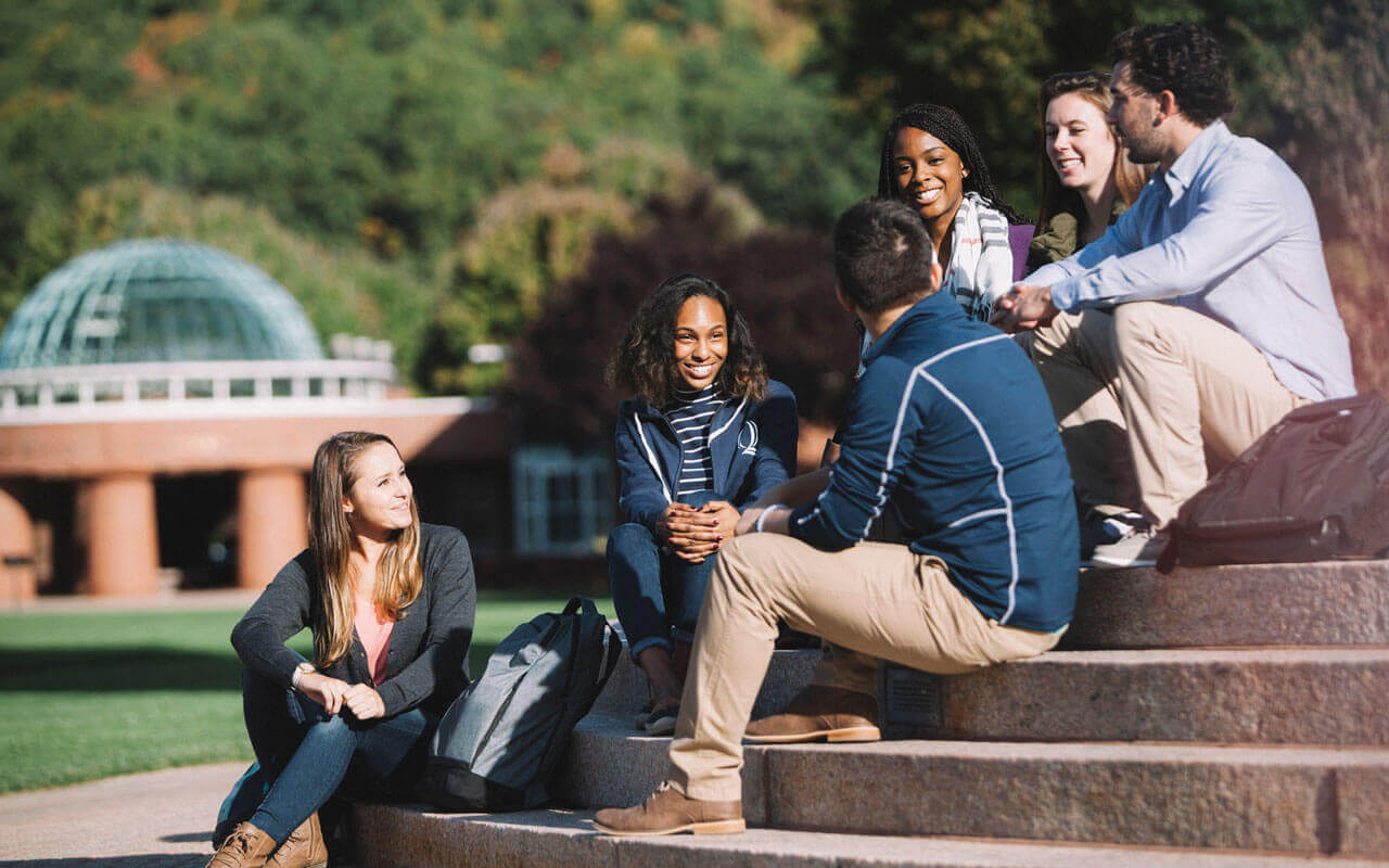 Students sitting on steps in front of library